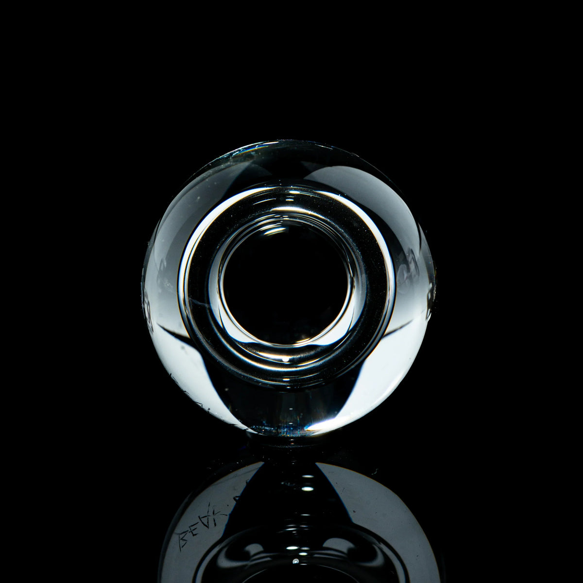 Clear toroidal glass marble with reflective surface on black background