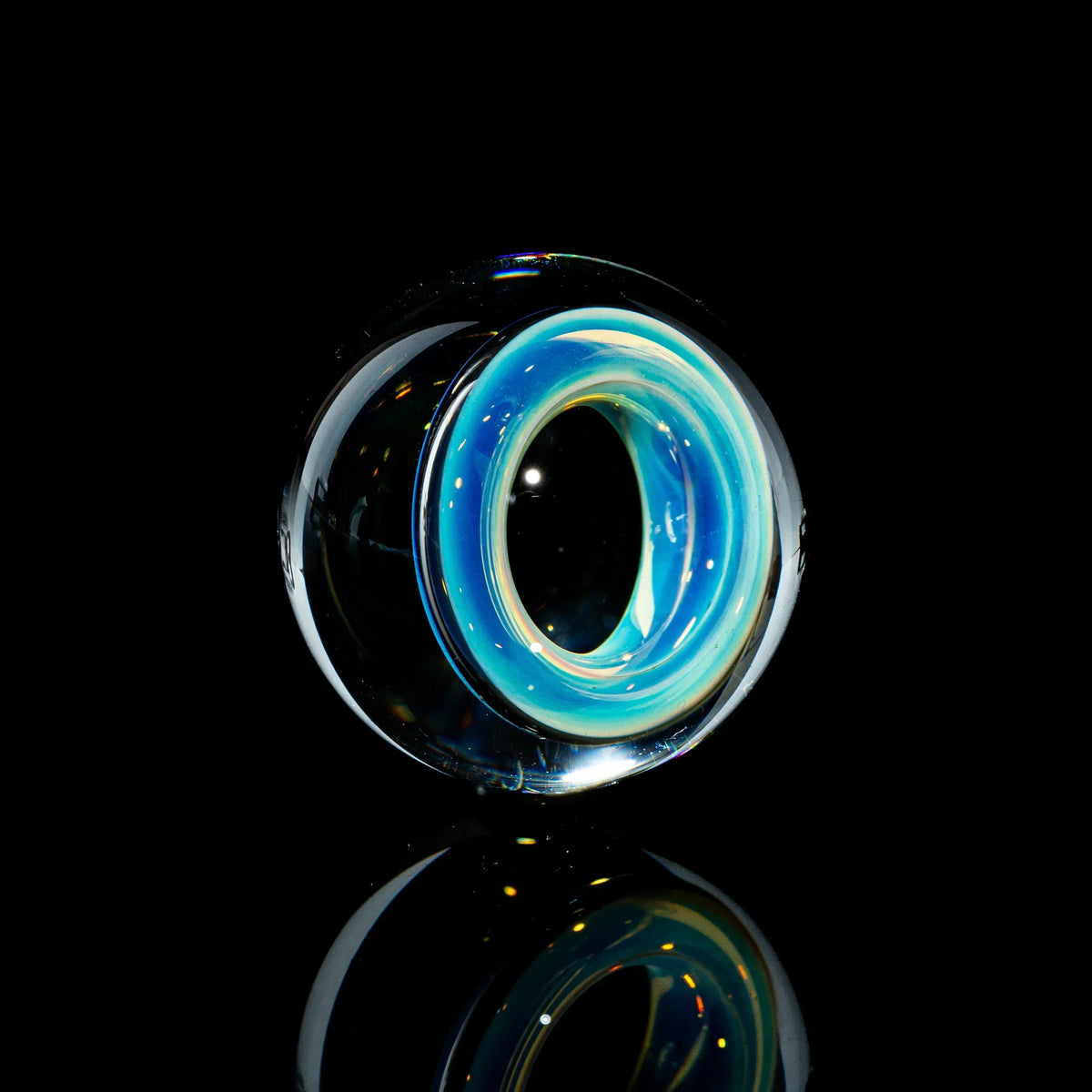 Toroidal glass marble with blue and yellow swirls on a black reflective background