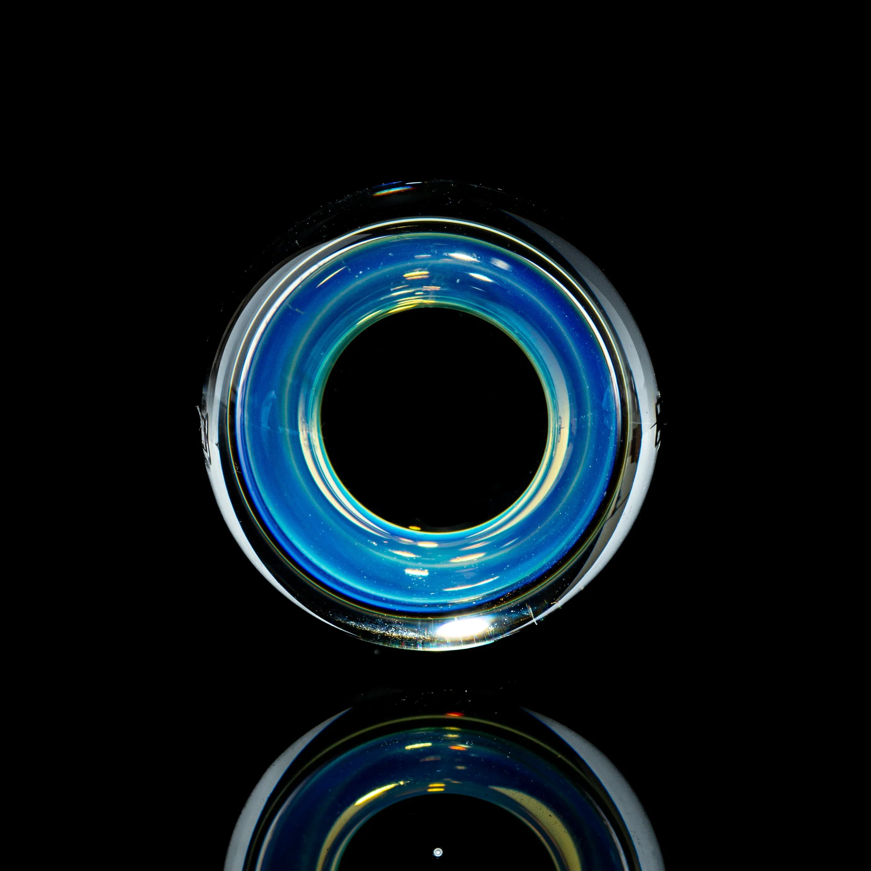 Blue toroidal glass marble with vibrant reflections on a black background