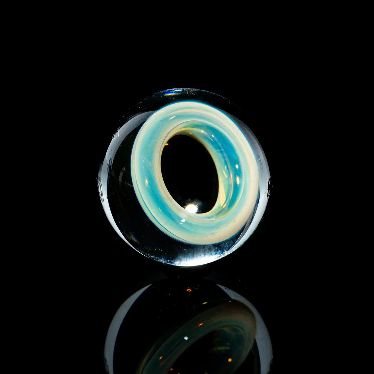 Toroidal glass marble with blue and yellow swirl design on a black reflective surface