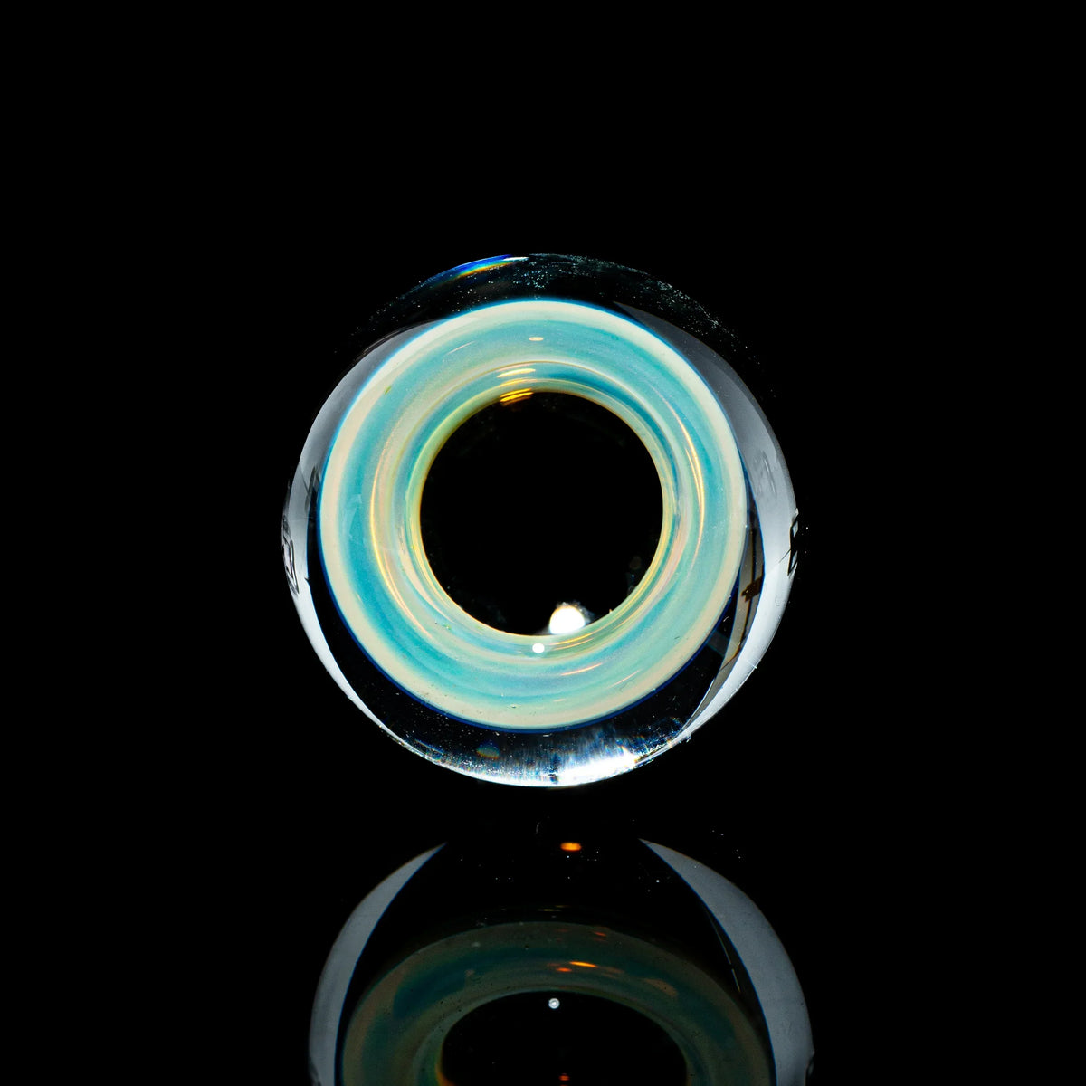 Toroidal glass marble with blue and yellow accents on a black reflective surface