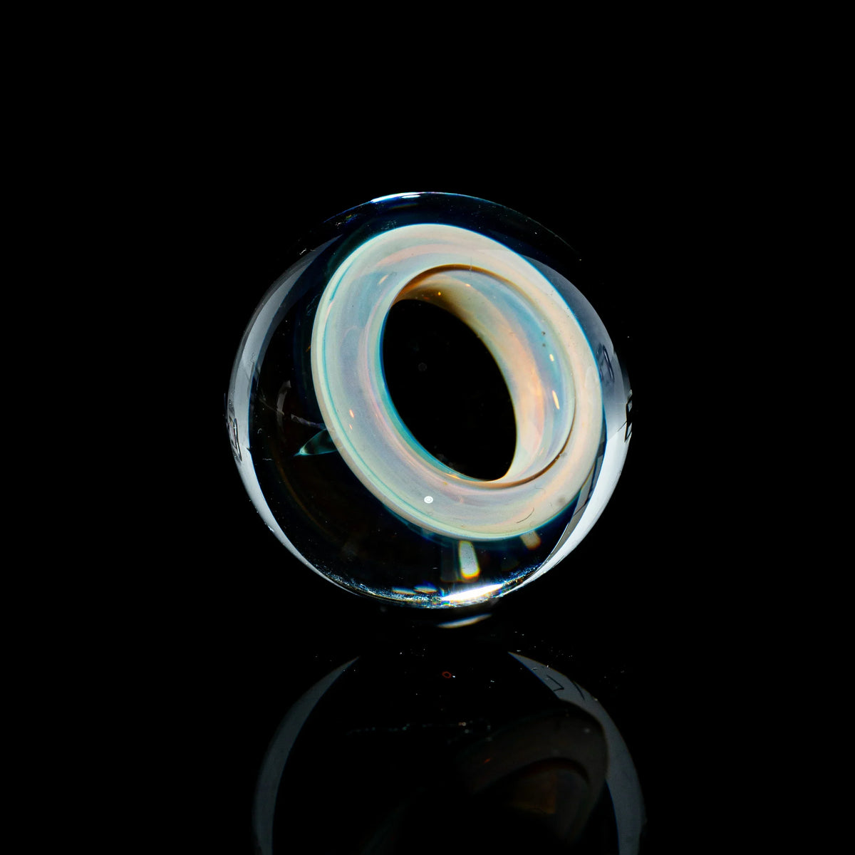 Toroidal glass marble with iridescent ring design on black background