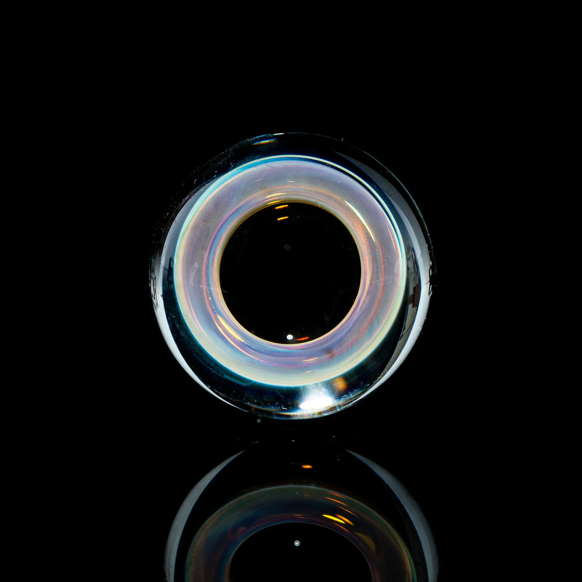 Toroidal glass marble with iridescent colors on a black reflective background