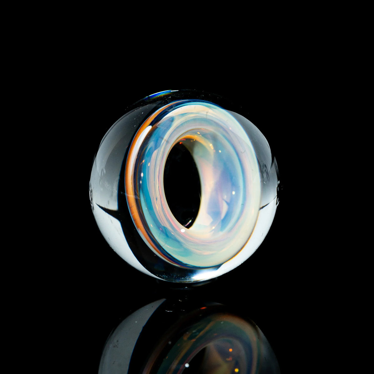 Toroidal glass marble with opalescent swirl, displayed on a black background