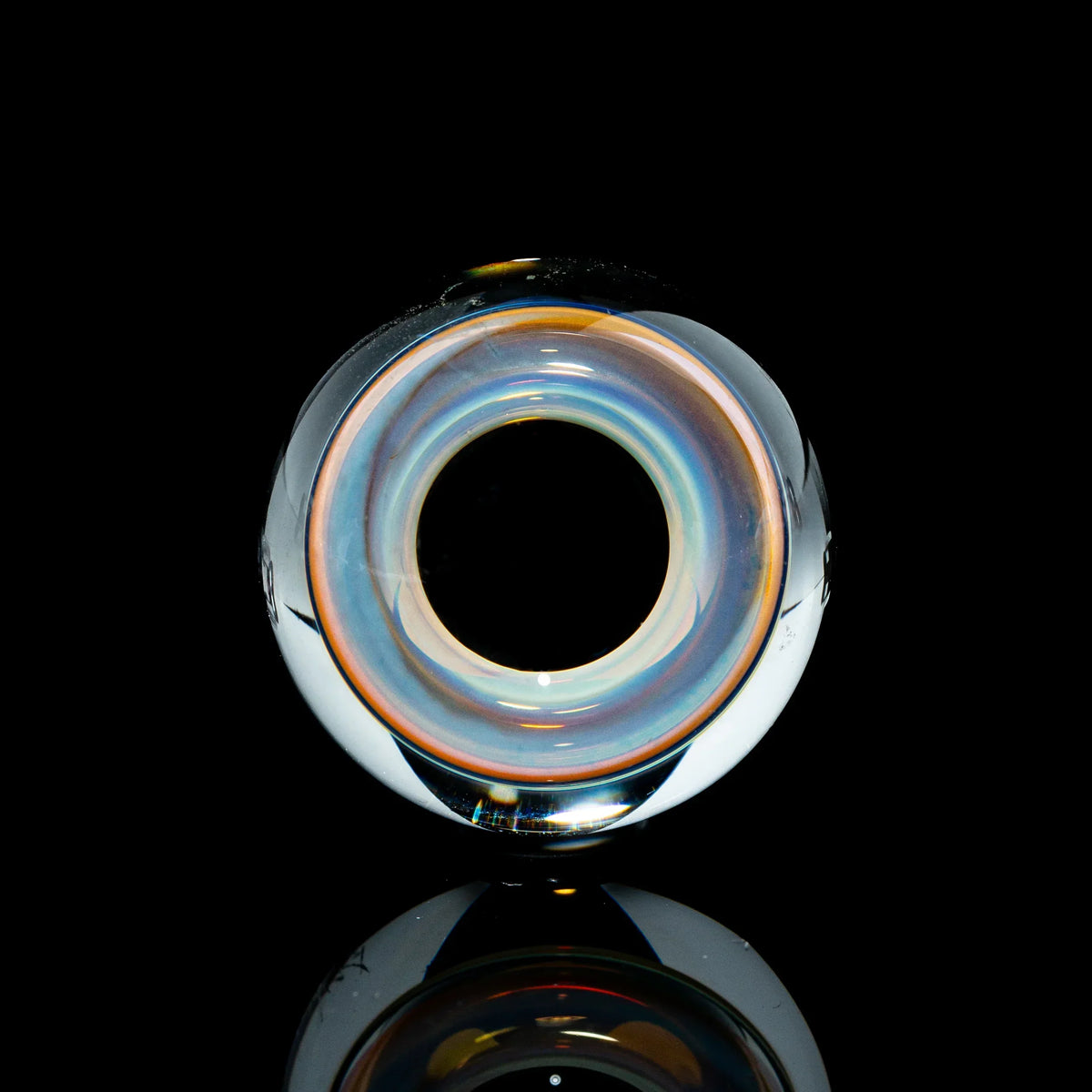 Toroidal glass marble with iridescent colors on a black background