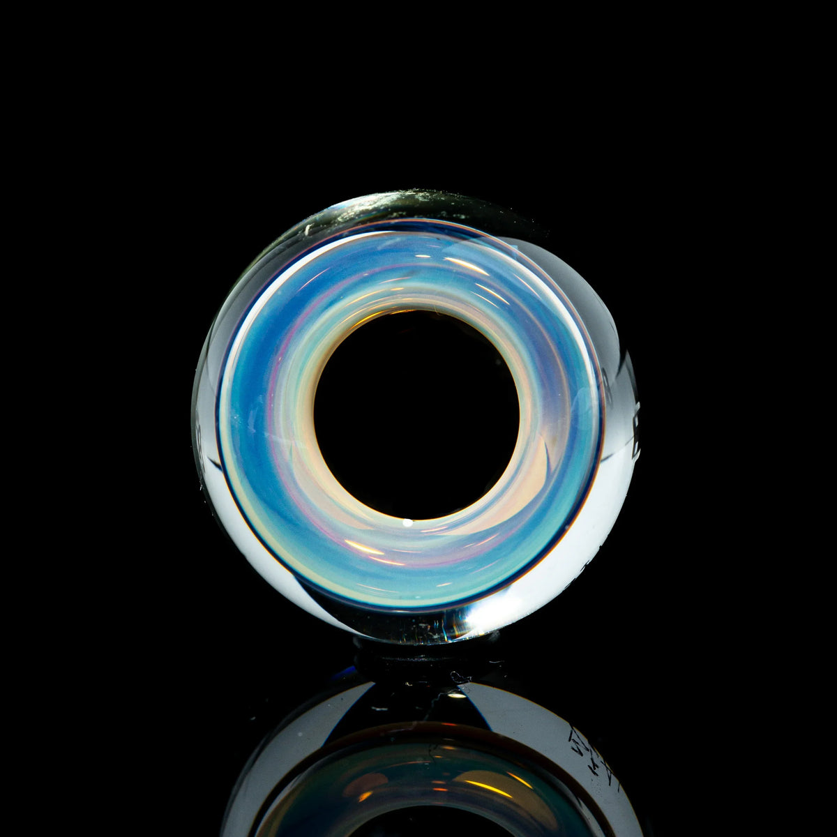 Toroidal glass marble with iridescent blue and clear swirls on a black background