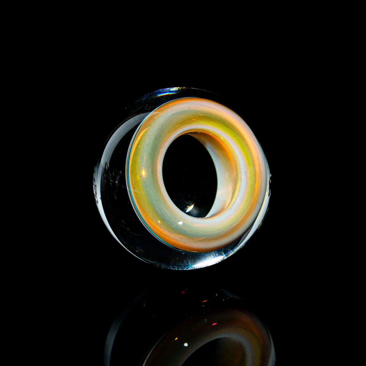 Toroidal glass marble with iridescent core on black background, heady glass accessory