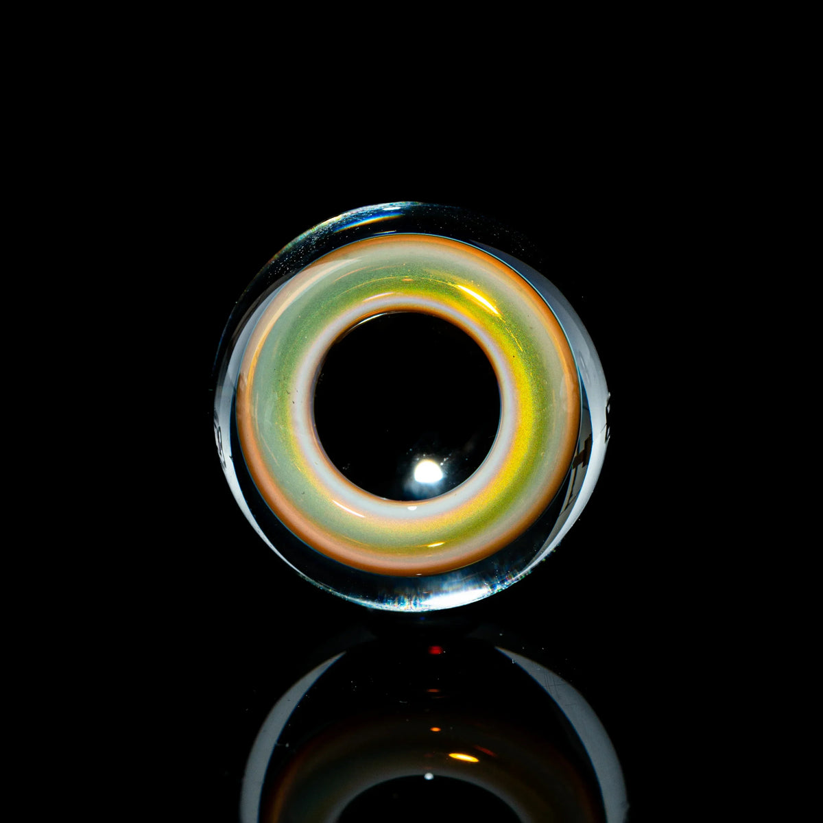 Toroidal glass marble with colorful ring design on black reflective background