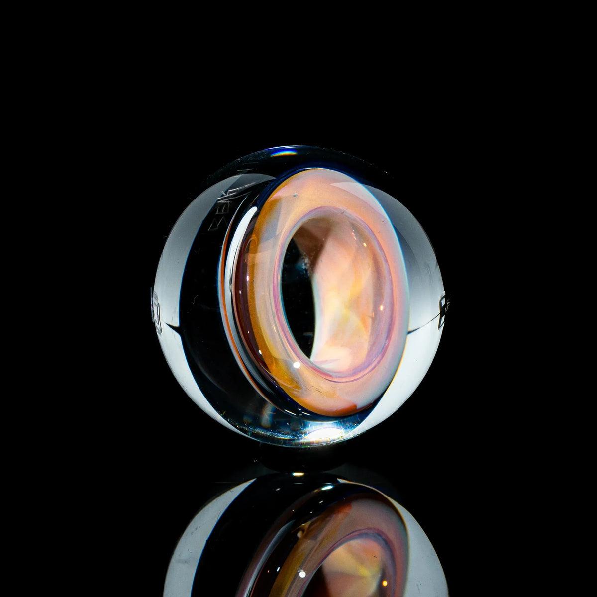 Toroidal glass marble with iridescent orange and yellow core on black background