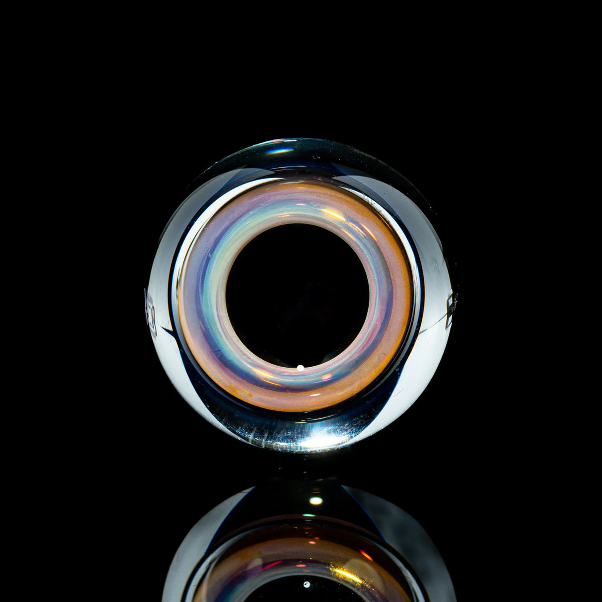 Toroidal glass marble with iridescent orange and purple hues on black background