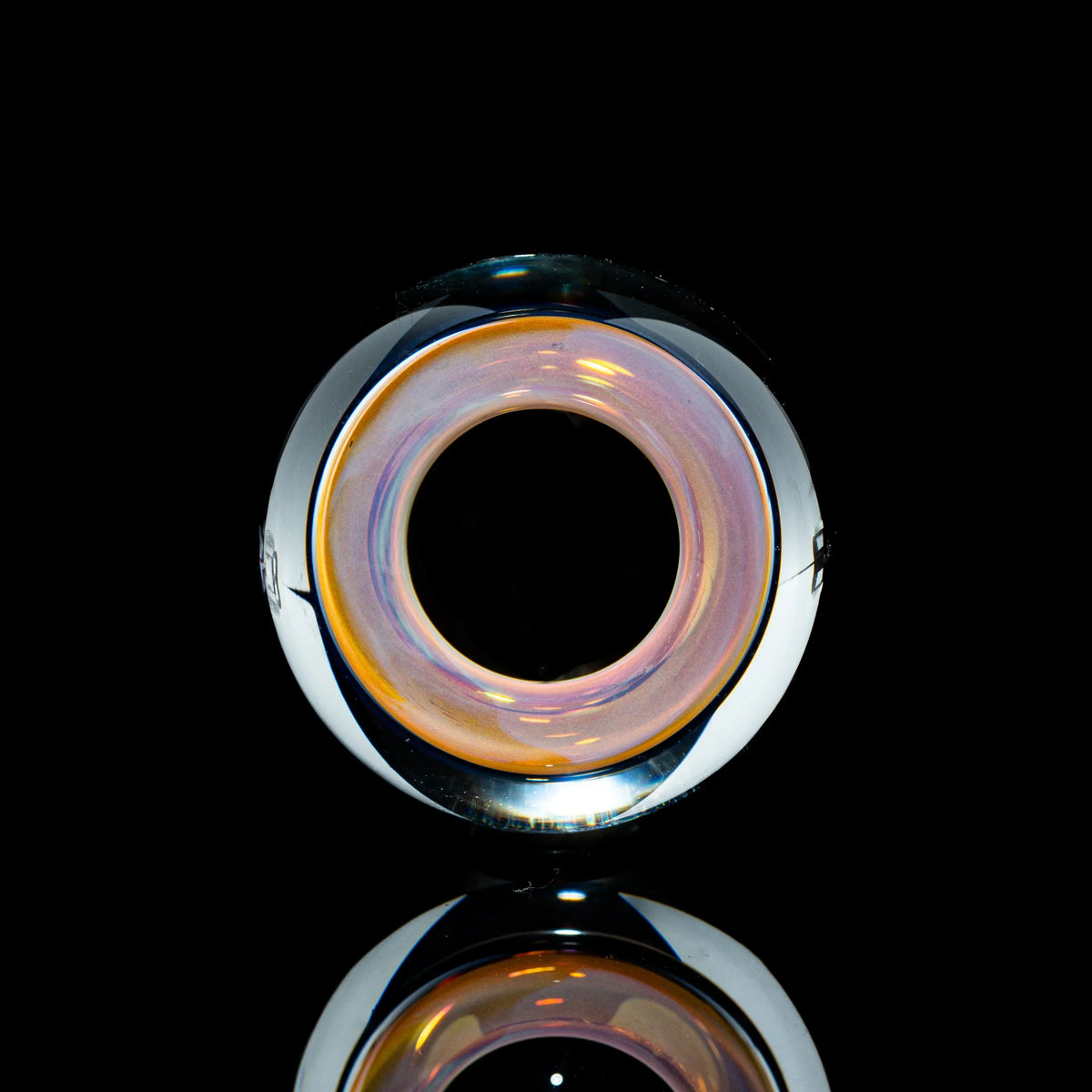 Toroidal glass marble with iridescent colors on black reflective background