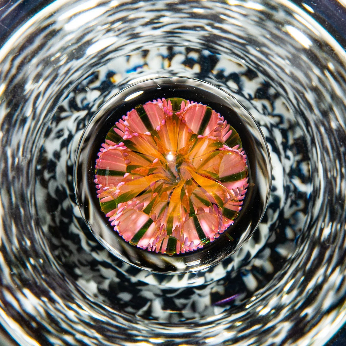Close-up of intricate heady glass art with vibrant pink and orange floral design