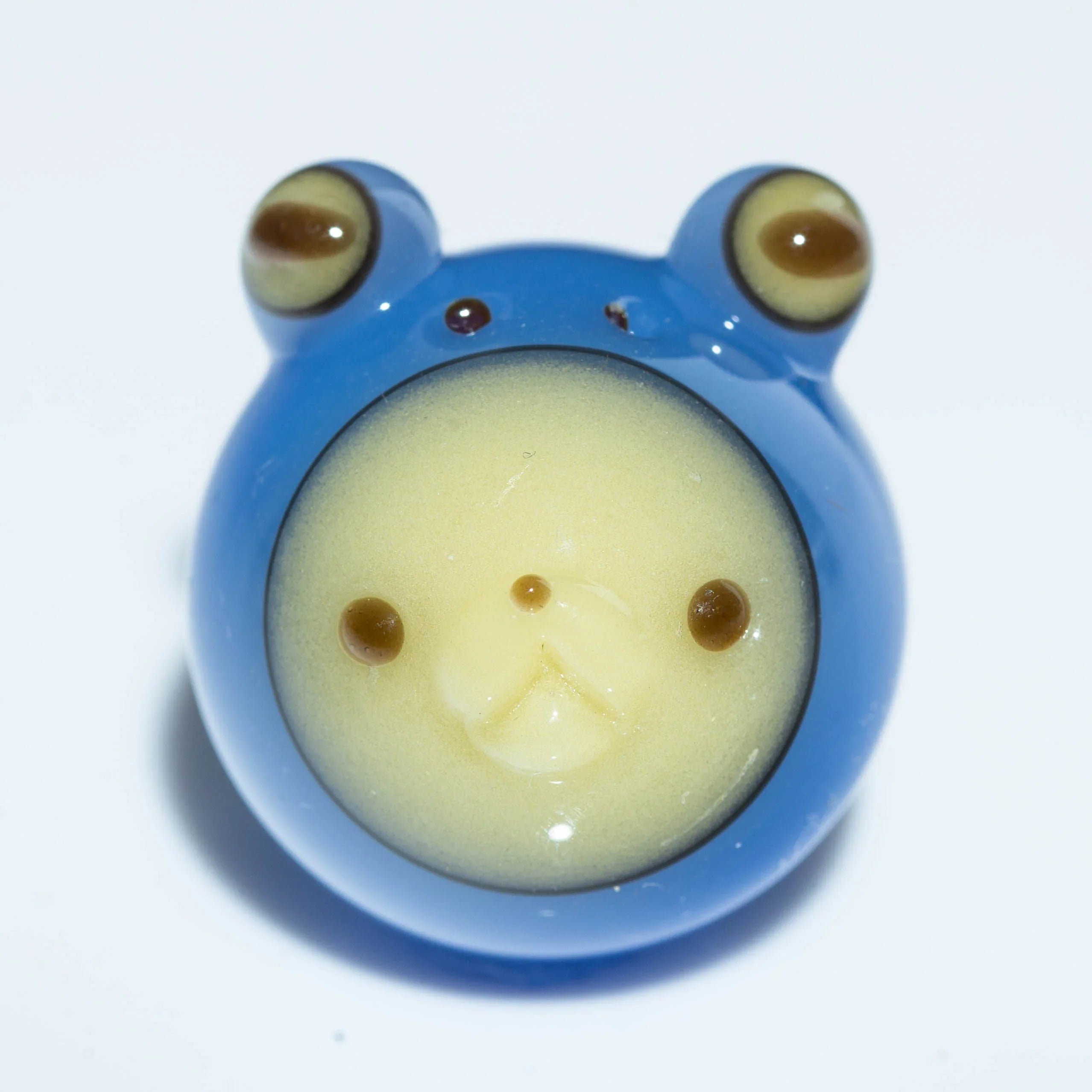 Blue glass carb cap shaped like a bear with yellow face, heady glass accessory