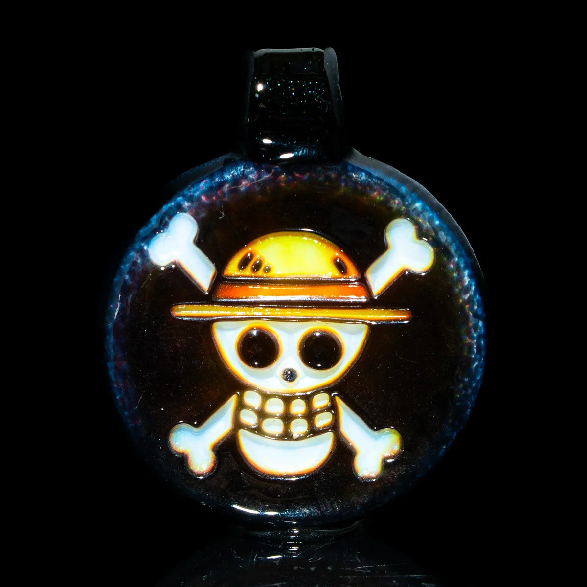 Handcrafted glass pendant with cartoon skull and crossbones design, set on dark background