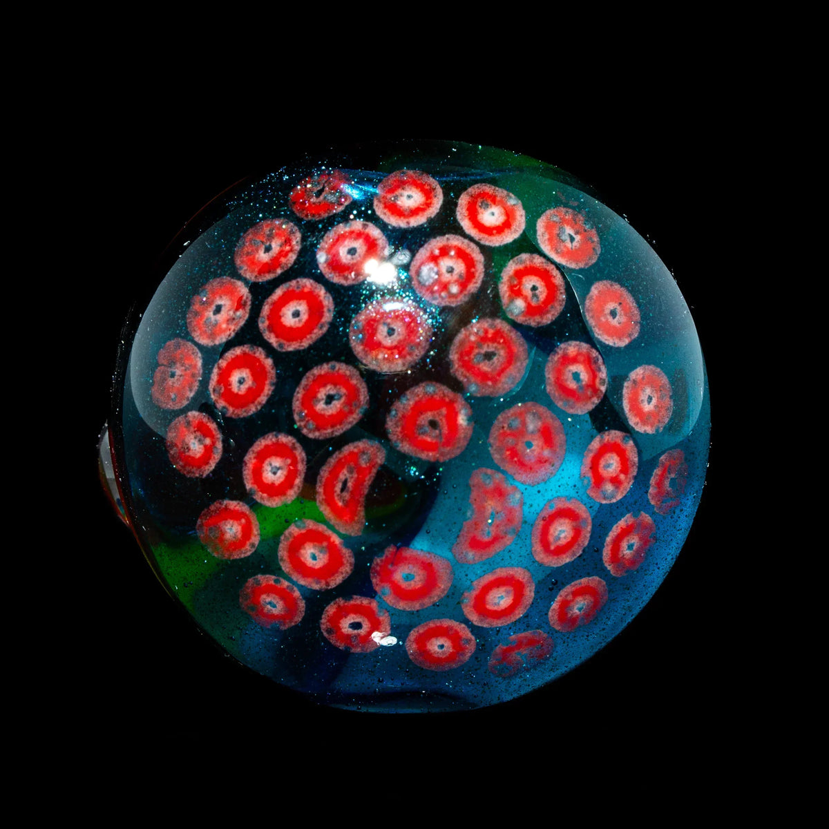 Hand-blown glass marble with colorful red and blue millefiori patterns on a black background