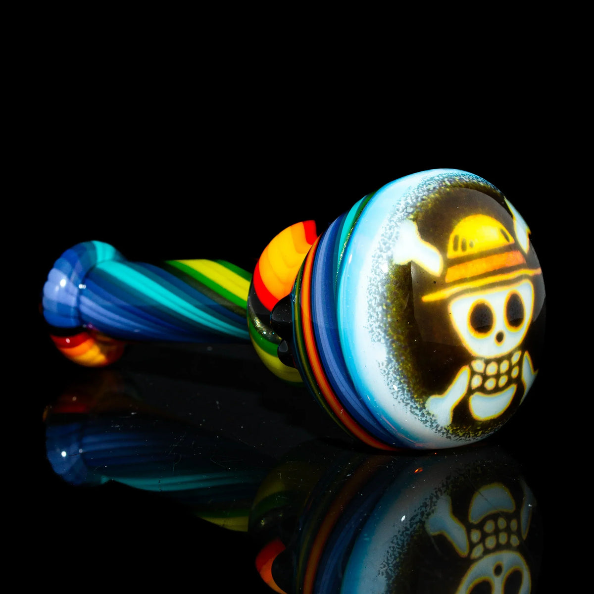 Colorful glass spoon pipe with rainbow swirl pattern and cartoon skull design on bowl