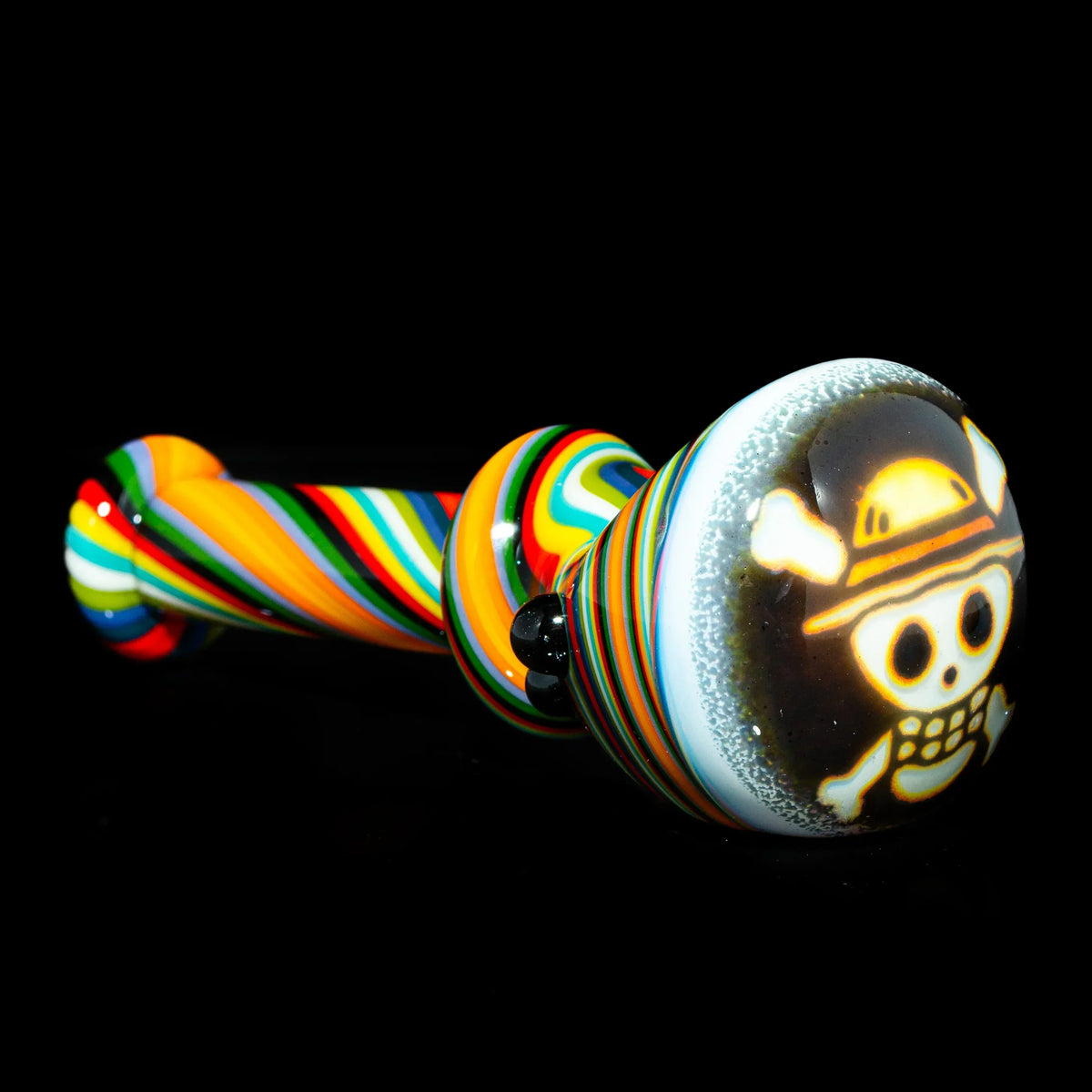 Colorful glass spoon pipe with rainbow swirl design and skull art on the bowl, on black background.
