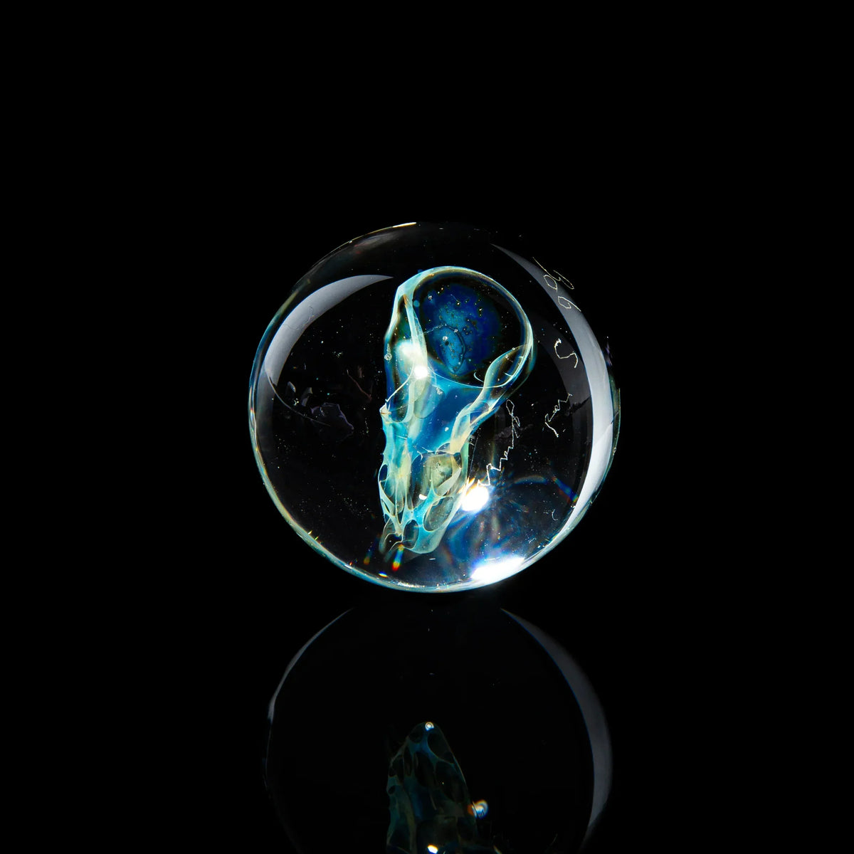 Hand-blown glass marble with a detailed skull design, art glass accessory on black background