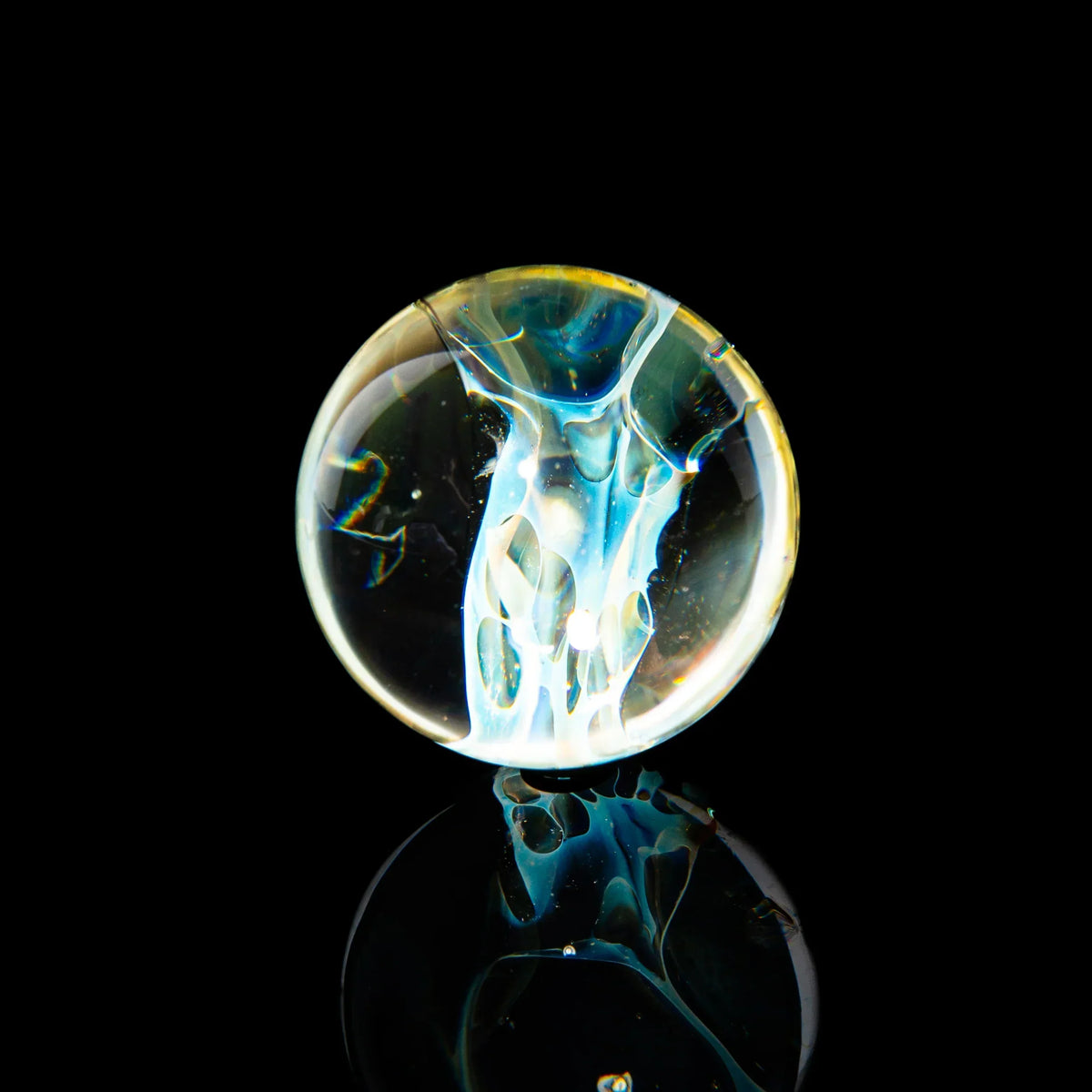 Hand-blown glass marble with intricate skull design, reflective surface, black background