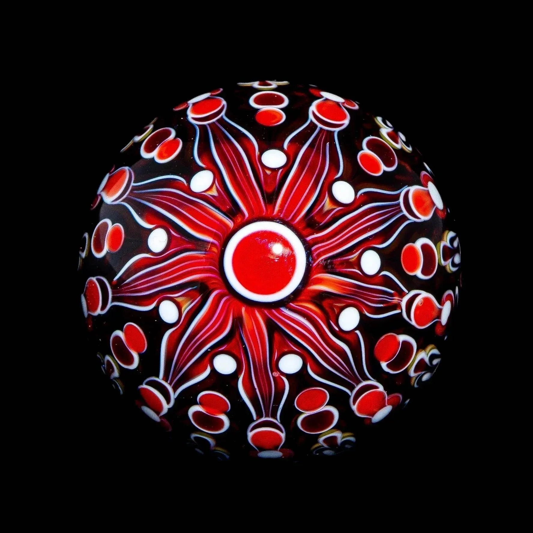 Handblown glass marble with red floral pattern and white dots on black background