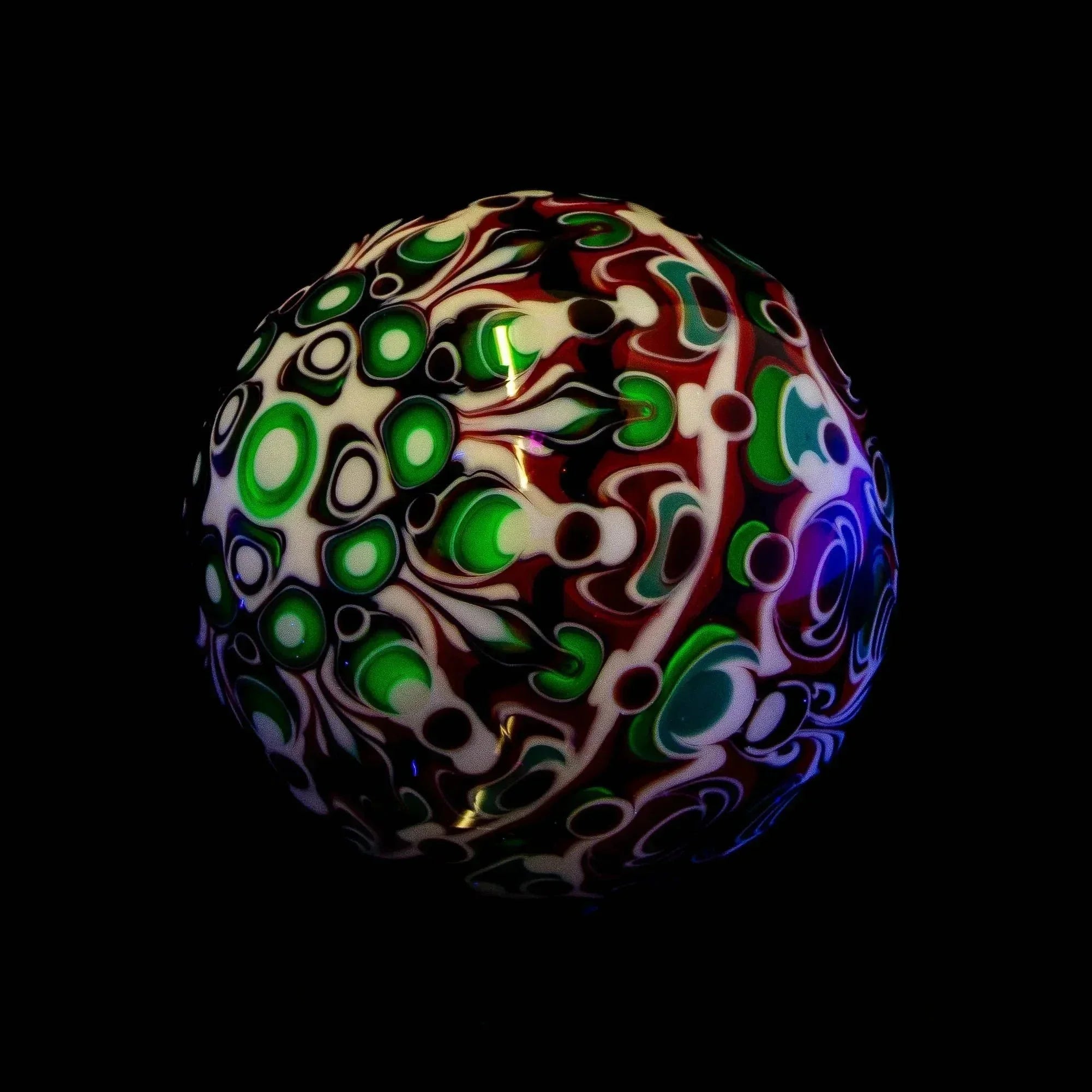 Heady glass marble with vibrant green, white, and red abstract patterns on black background