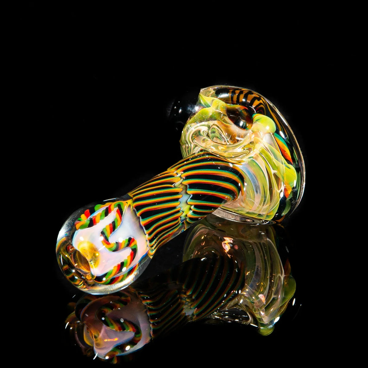 Colorful glass hand pipe with brown, green, and yellow reticello pattern on black background.