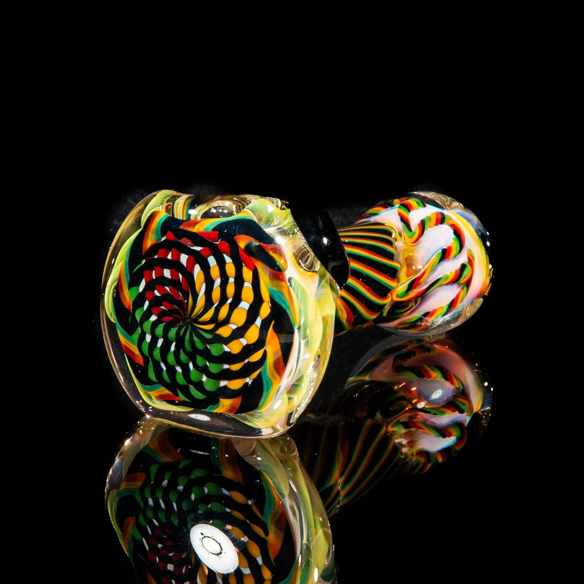 Colorful handblown glass spoon pipe with brown, green, and yellow reticello pattern on black background
