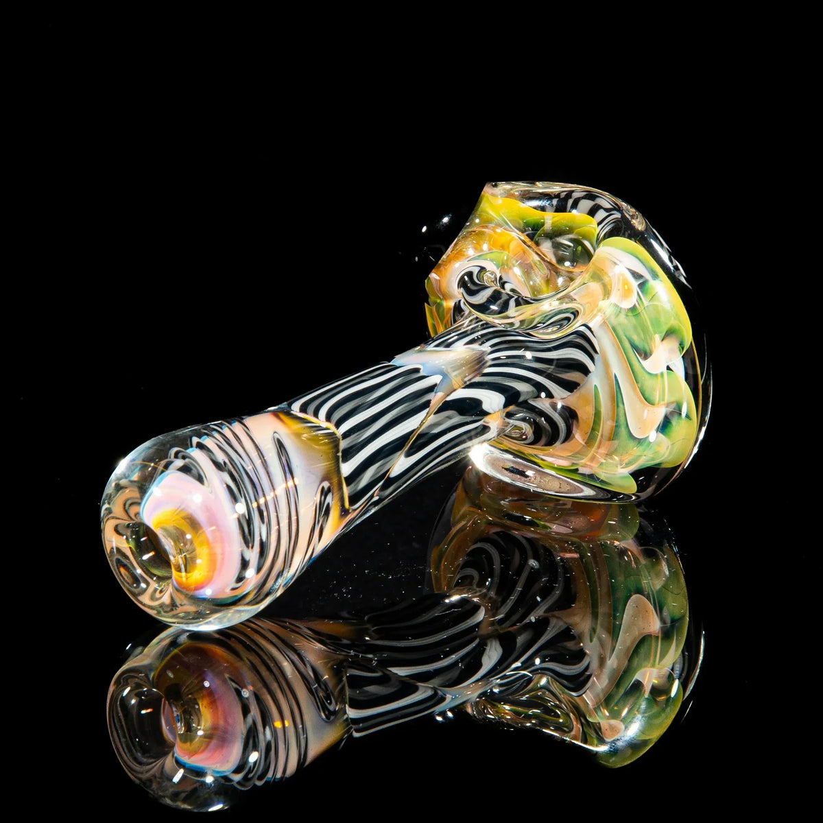 Gray, white, and black glass spoon pipe with reticello pattern on reflective black background.