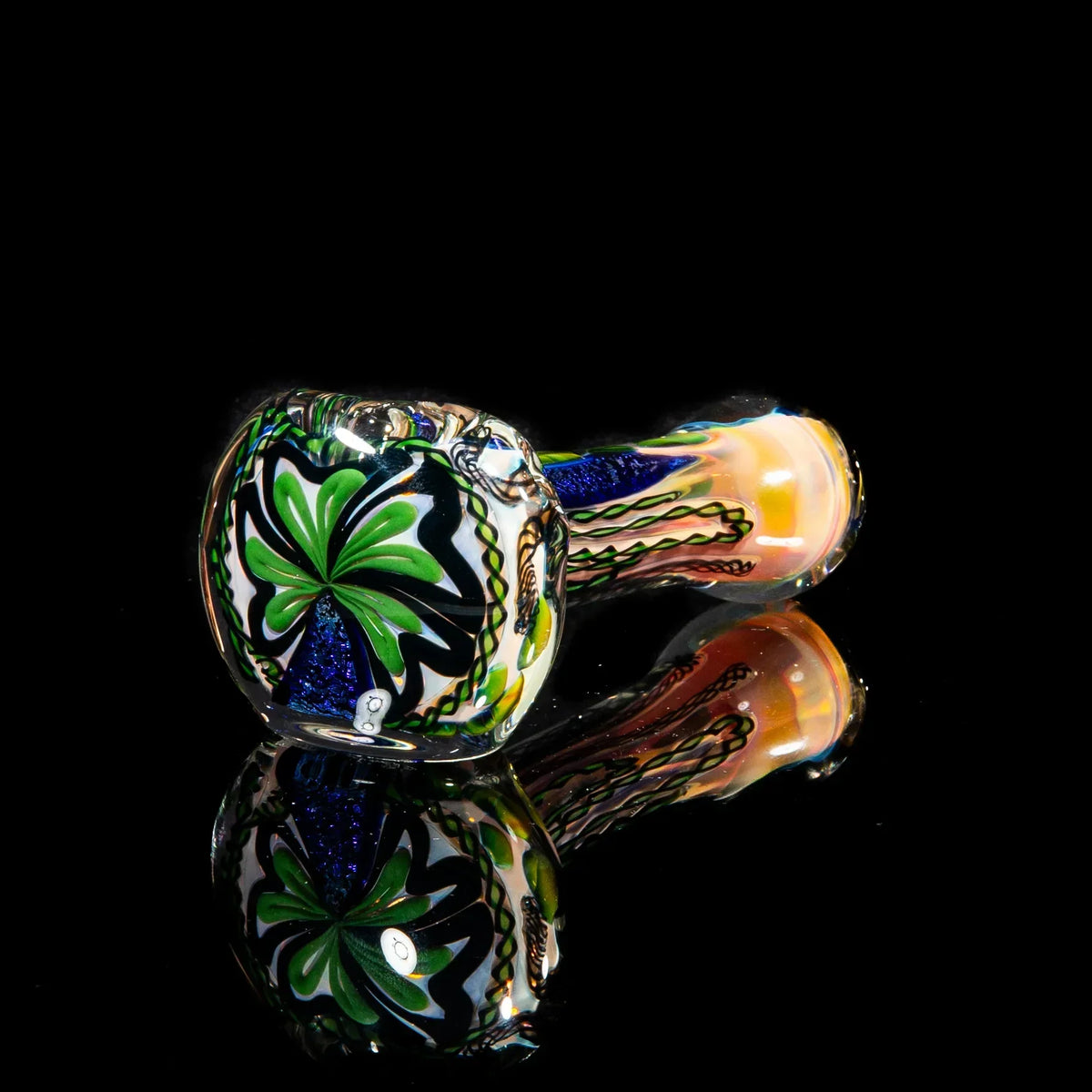 Colorful hand-blown glass pipe with green and blue dichroic accents on black background