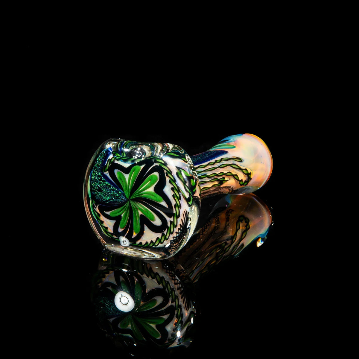 Hand-blown glass pipe with green dichroic strip and intricate swirl design on black background