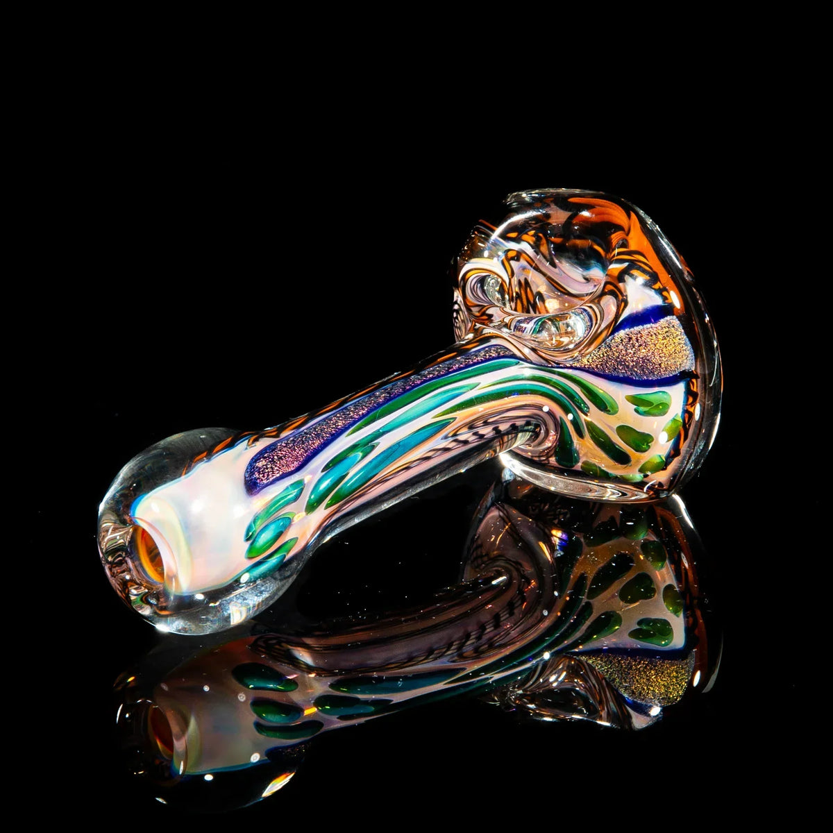 Colorful glass spoon pipe with orange, gold, and green accents on black background