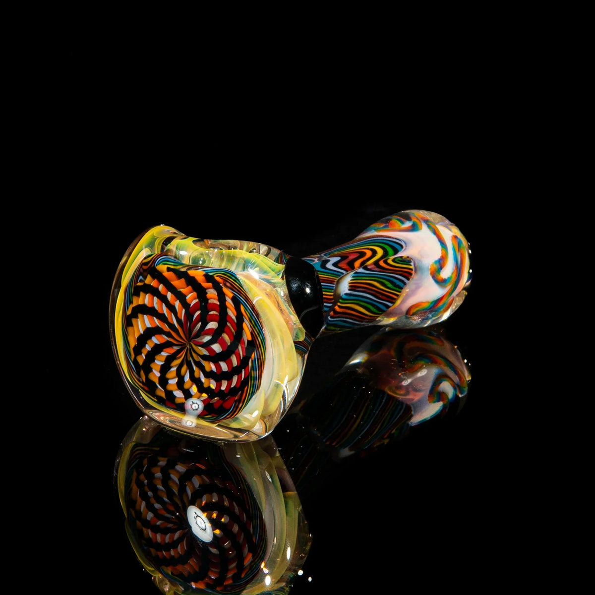 Heady glass spoon pipe with orange, yellow, and brown reticello swirl design on black background