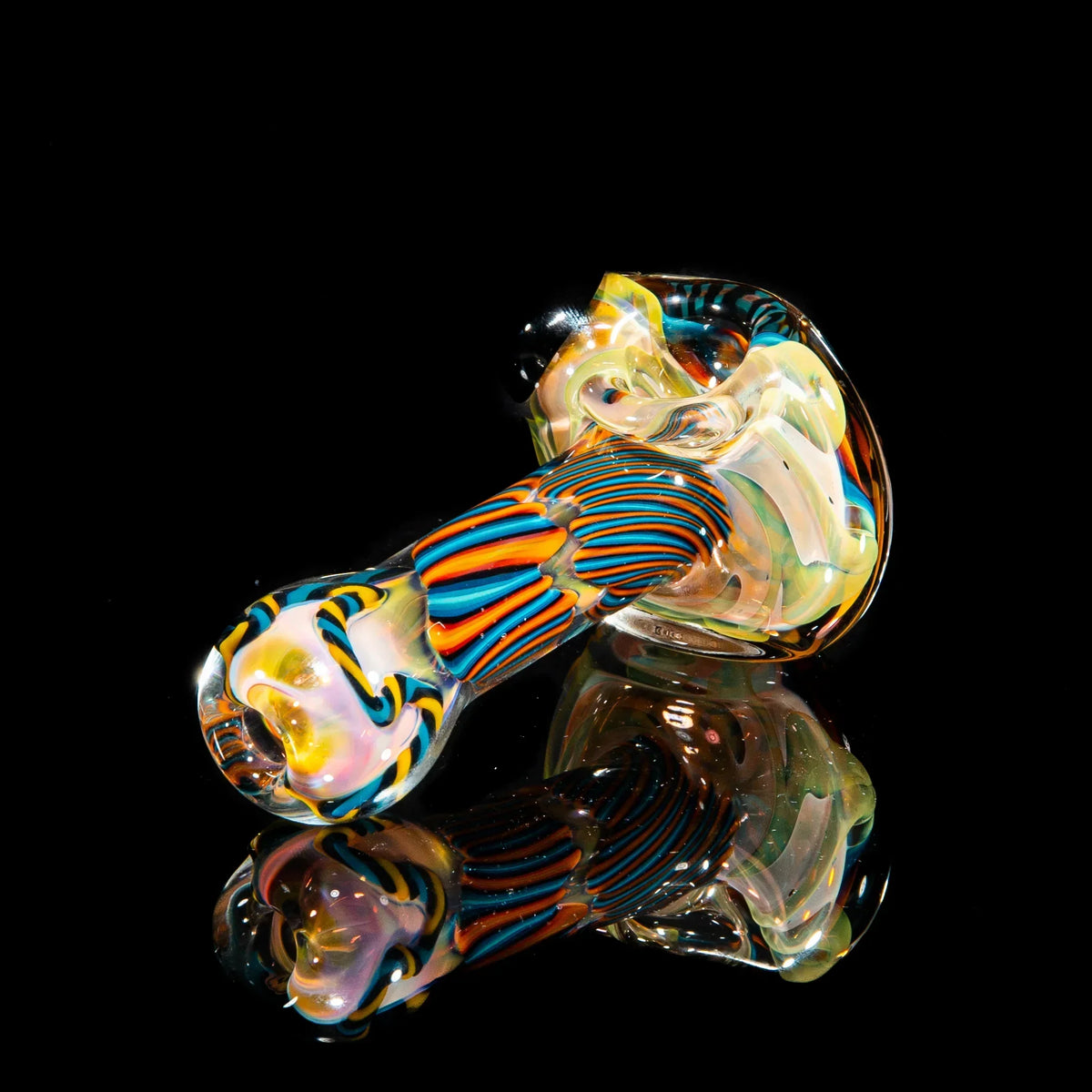 Hand-blown glass spoon pipe with orange, yellow, and teal reticello patterns on black background
