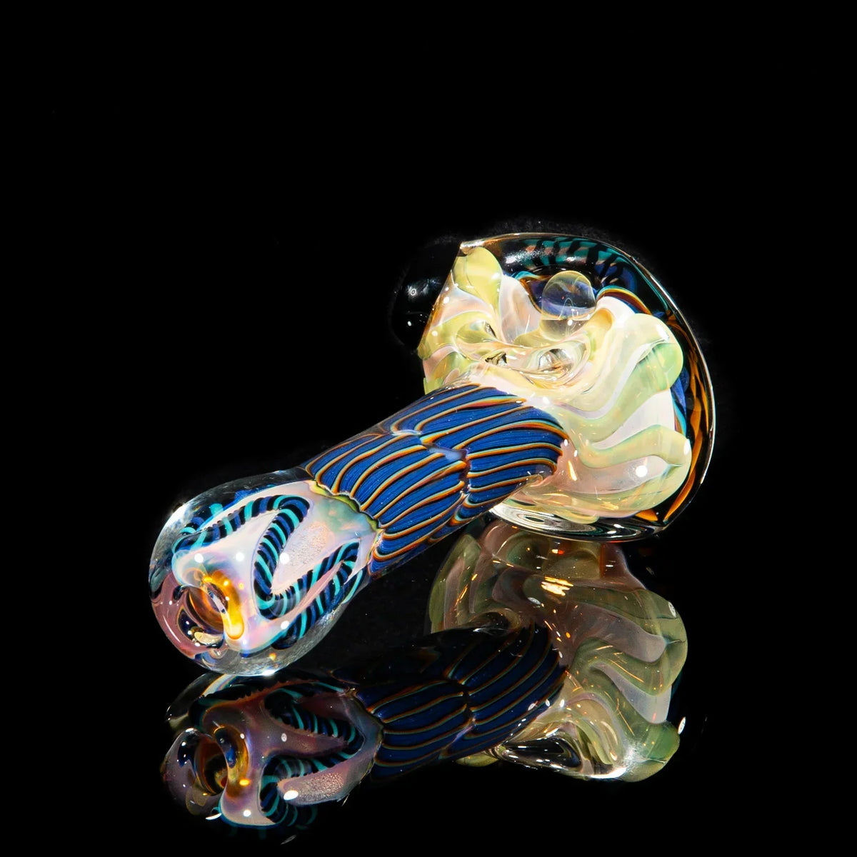 Handblown glass spoon pipe with purple, yellow, and teal reticello pattern on black background