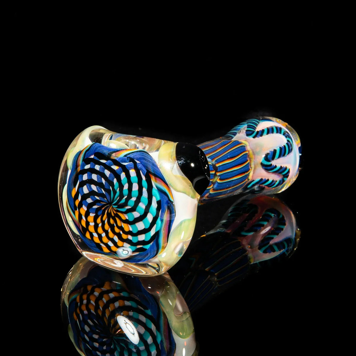 Colorful hand-blown glass pipe with purple, yellow, and teal reticello design on black background