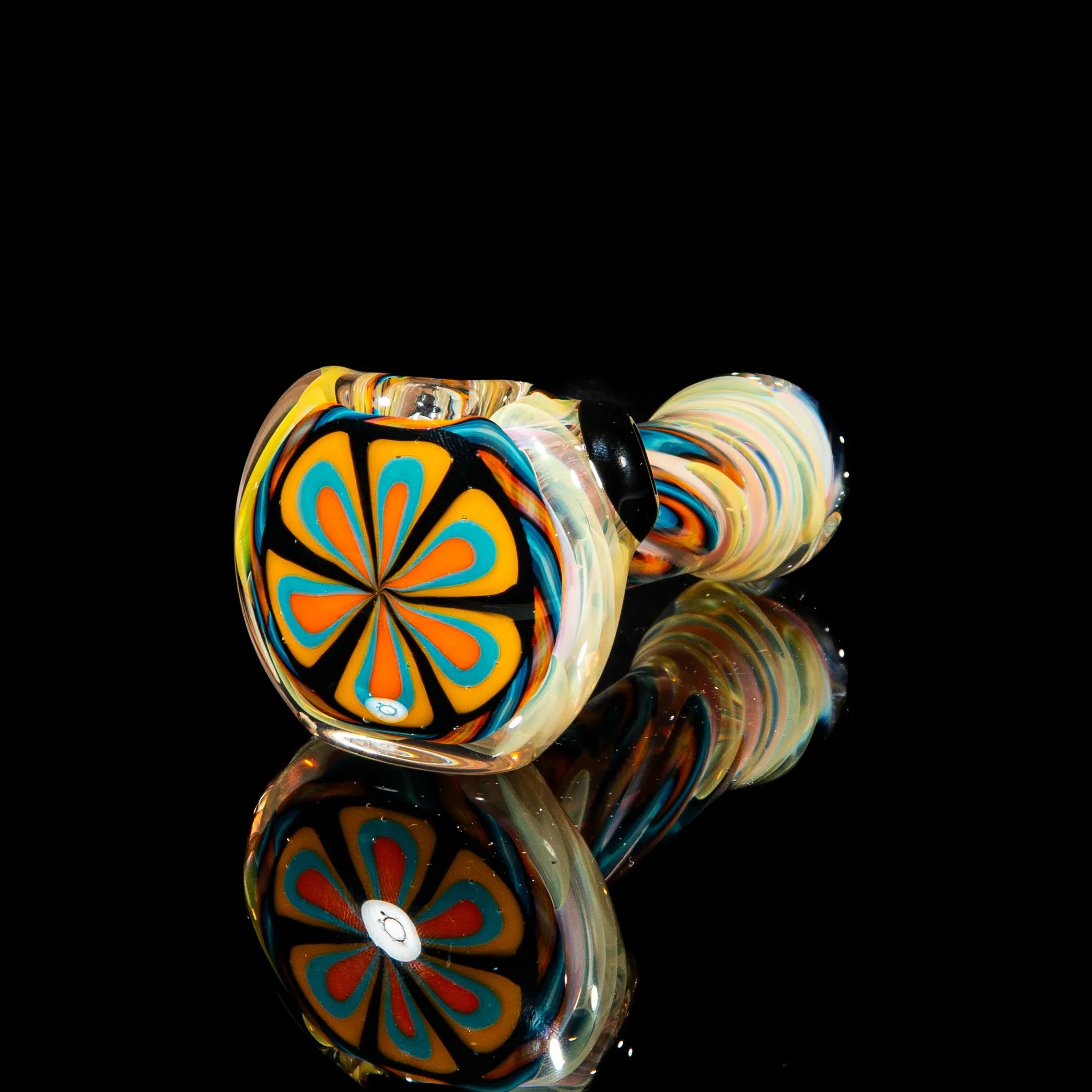 Colorful glass spoon pipe with yellow, teal, and orange flower pattern on black background.
