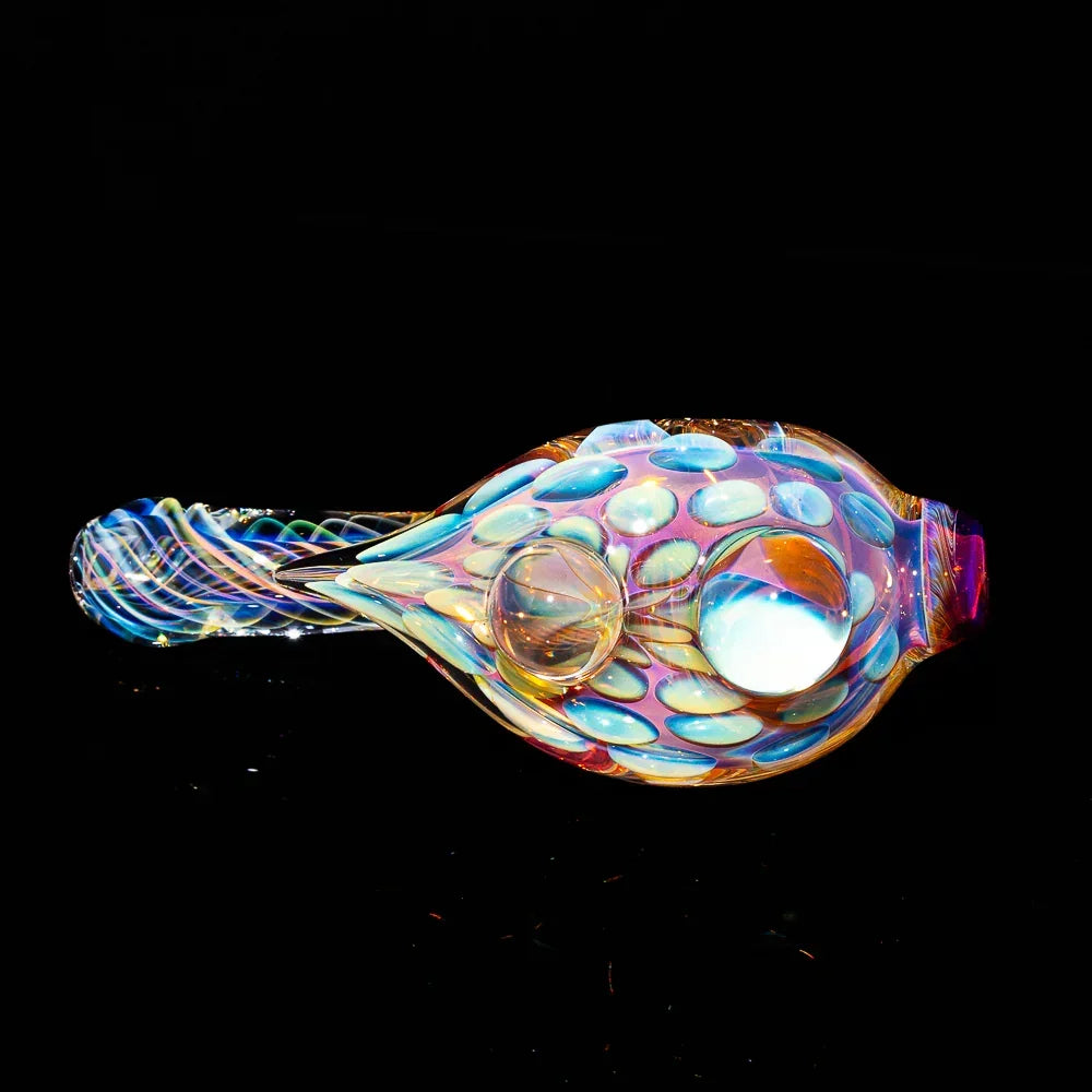 Colorful fumed glass hand pipe with textured, iridescent dots on a black background