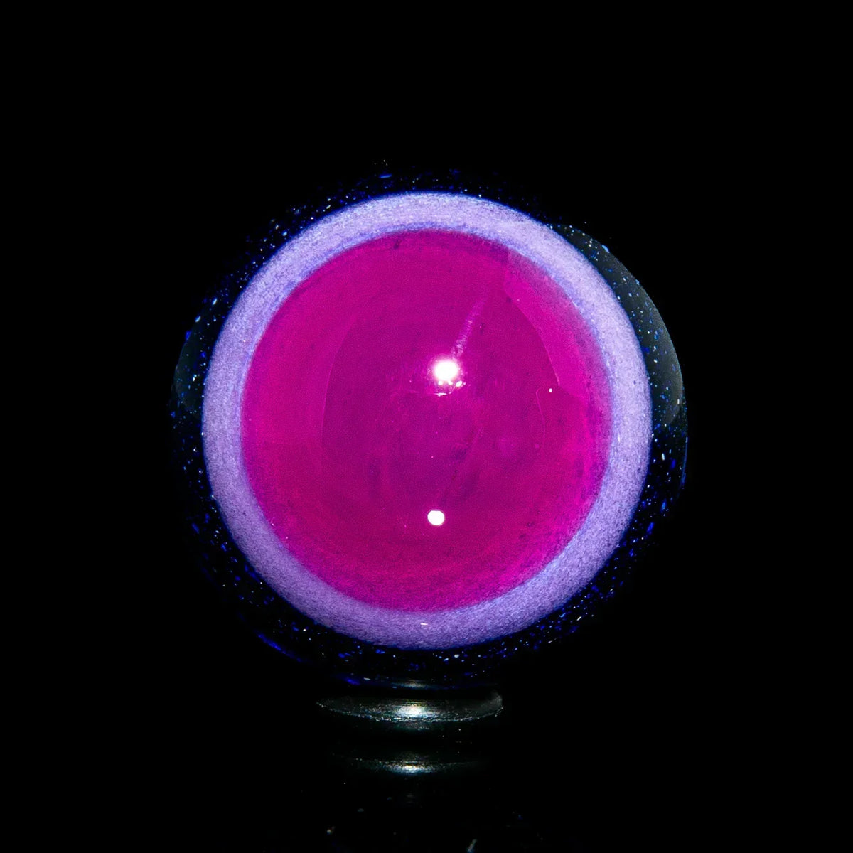 Pink and purple glass marble with a luminous core on a black background