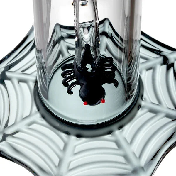 Glass water pipe with black spider design and web-shaped base, close-up view