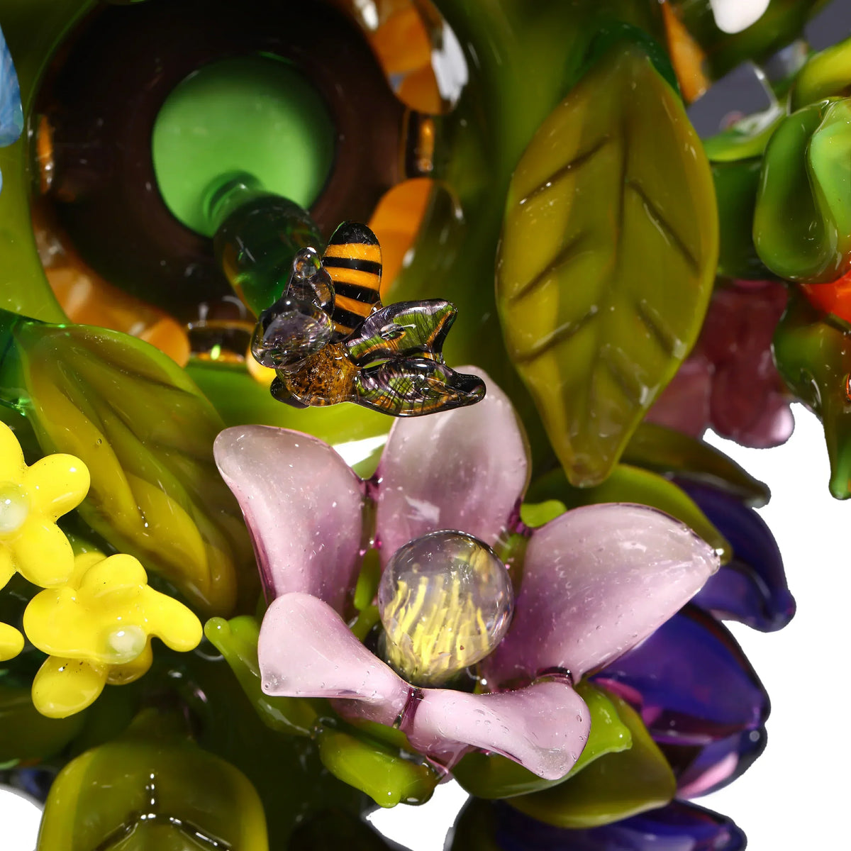 Detailed glass art with a bee, pink flower, green leaves, and yellow blossoms