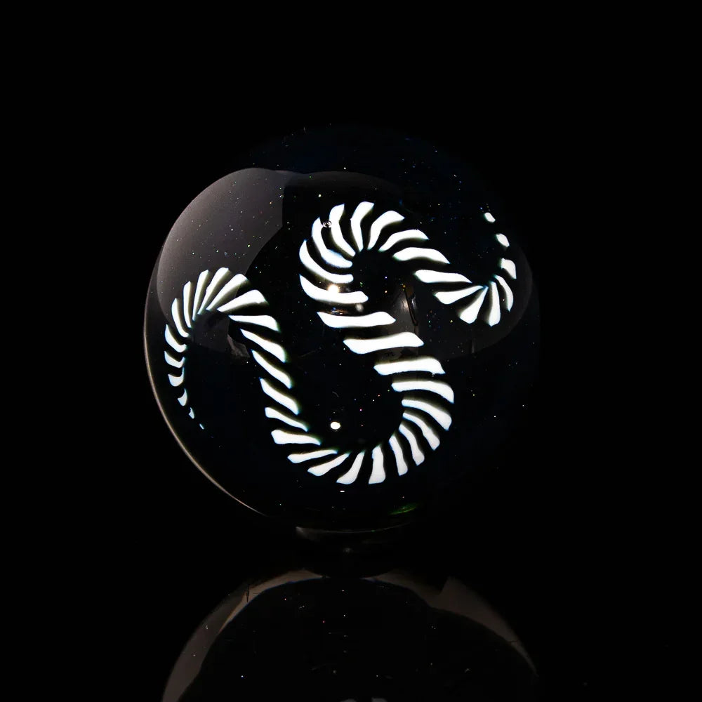 Handcrafted glass marble with swirling white spiral design on black background