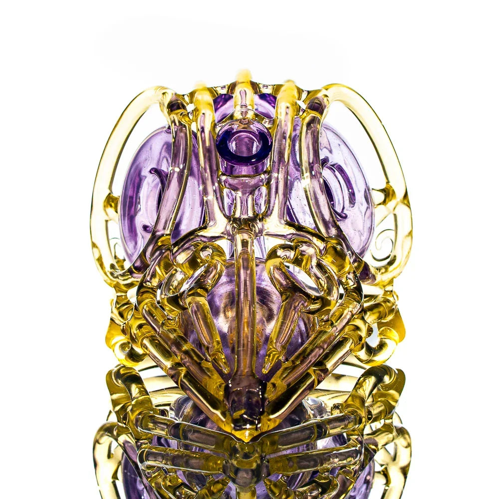 Intricate purple and yellow glass skull water pipe on white background, heady glass art piece