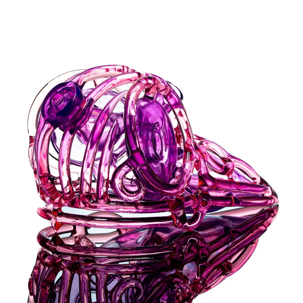 Pink and purple glass art pipe shaped like a skull, displayed on a reflective surface