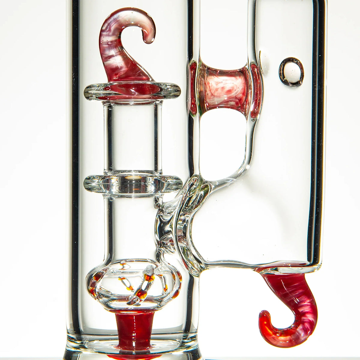 Close-up of intricate clear glass water pipe with red swirled hook accents