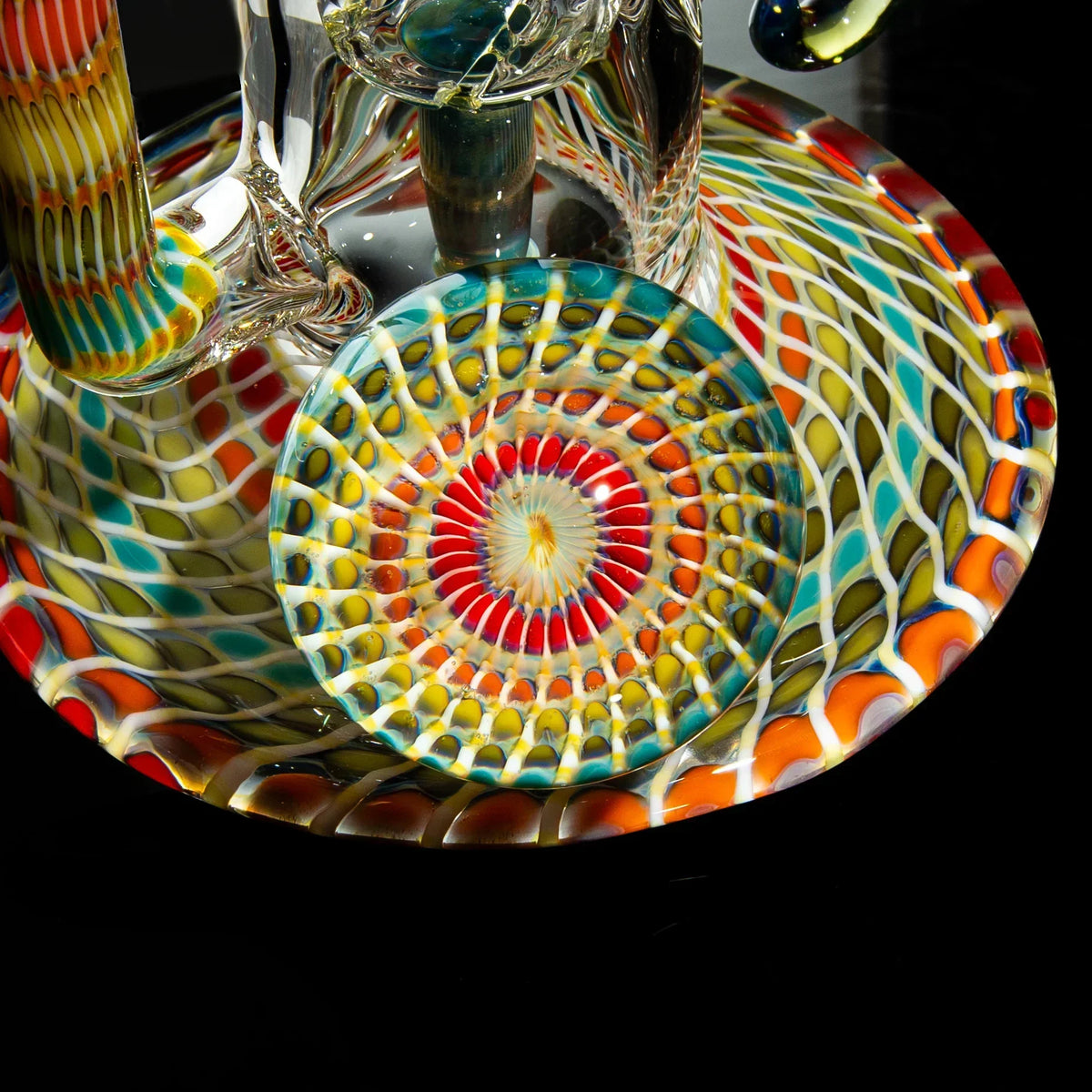 Close-up of colorful heady glass art piece with intricate spiral pattern on black background