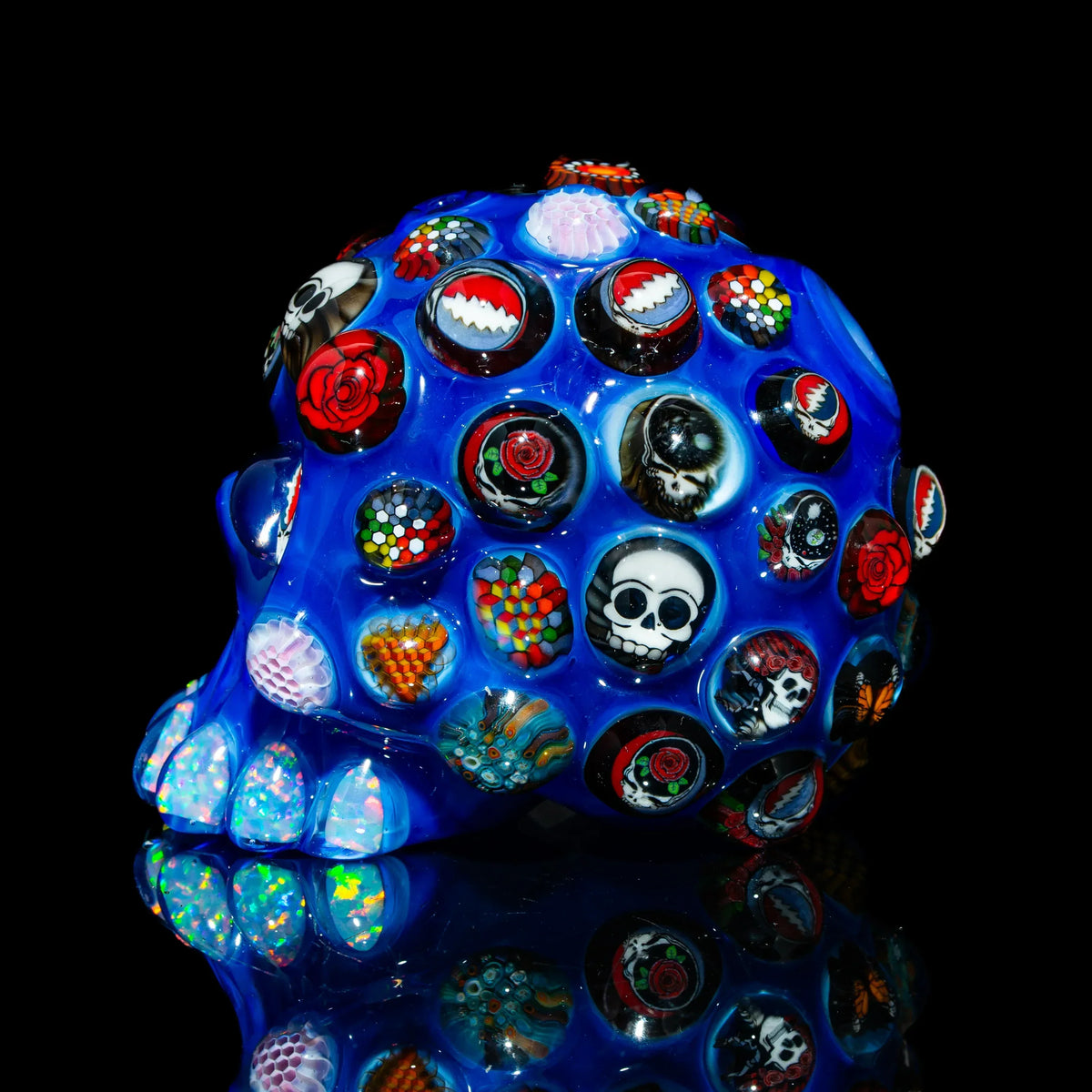 Heady glass blue skull art piece with colorful murrine designs, roses, and skull motifs