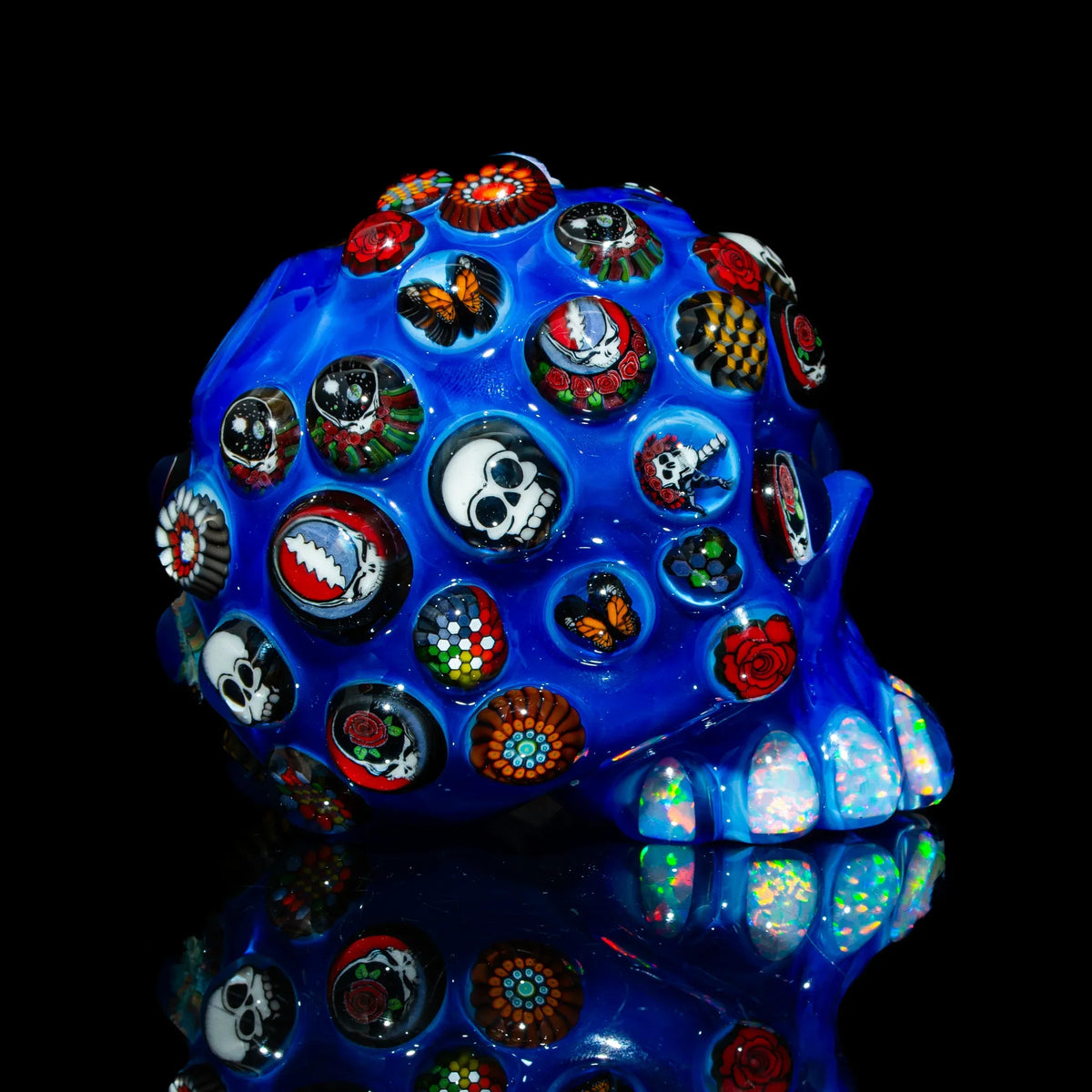 Blue glass skull with colorful millefiori designs, skulls, butterflies, and roses