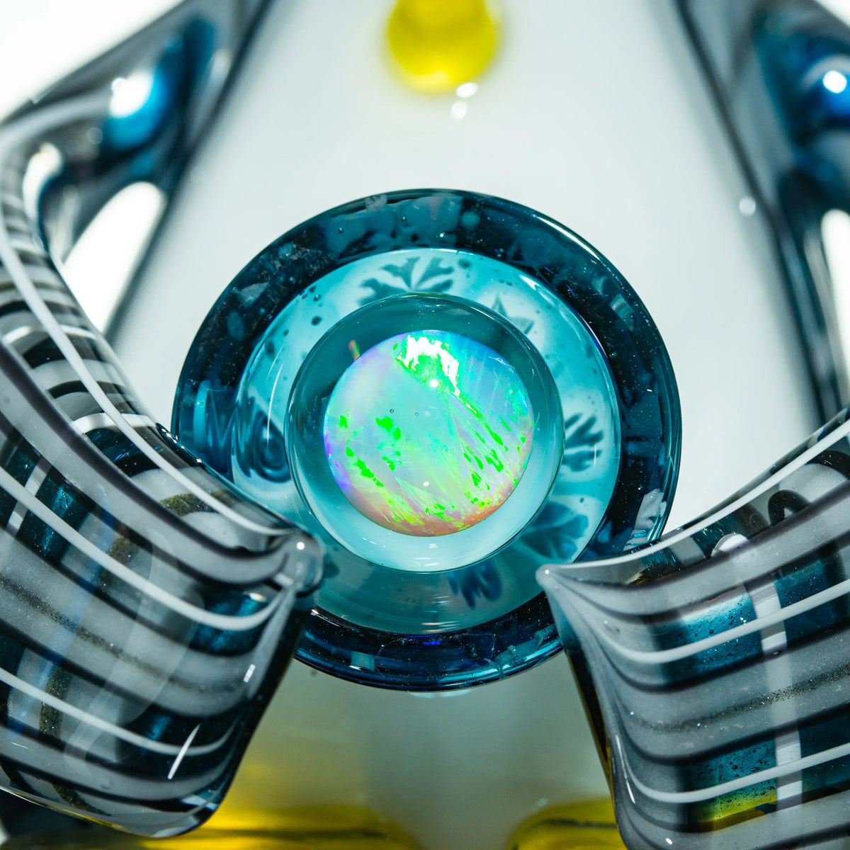 Close-up of intricate heady glass art piece with opal marble and blue striped accents