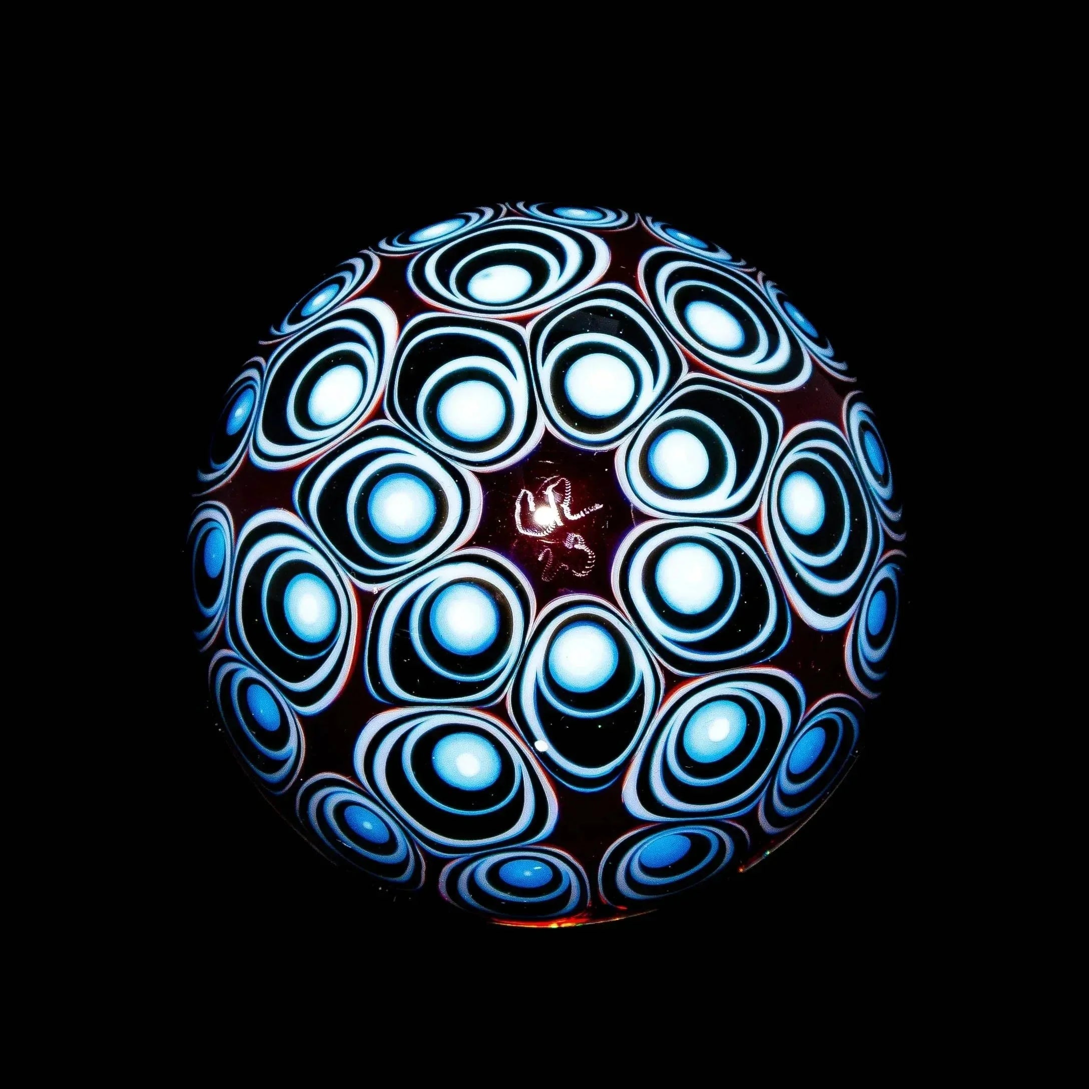 Intricate heady glass marble with blue op-art pattern, artisan glasswork on black background