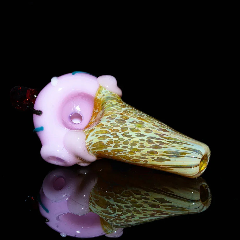 Glass spoon pipe shaped like a strawberry ice cream cone with sprinkles on black background